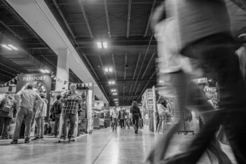 A black and white photo of people walking in a store.