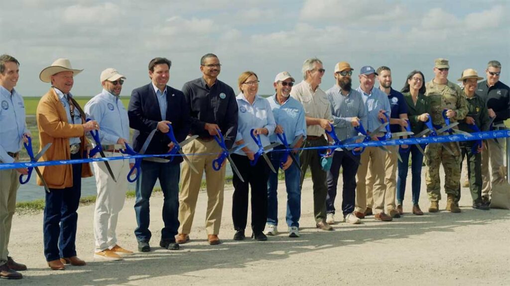 A group of people cutting a ribbon at a ribbon cutting ceremony.