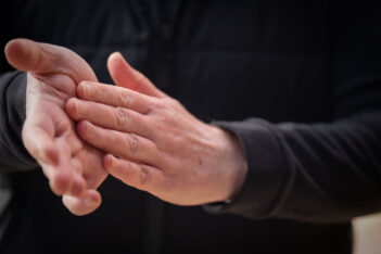 A man is putting his hands together in front of a camera.