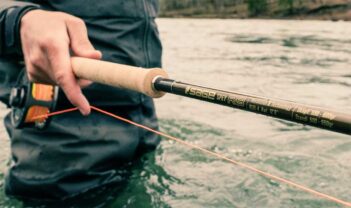 A person holding a fly rod in the water.