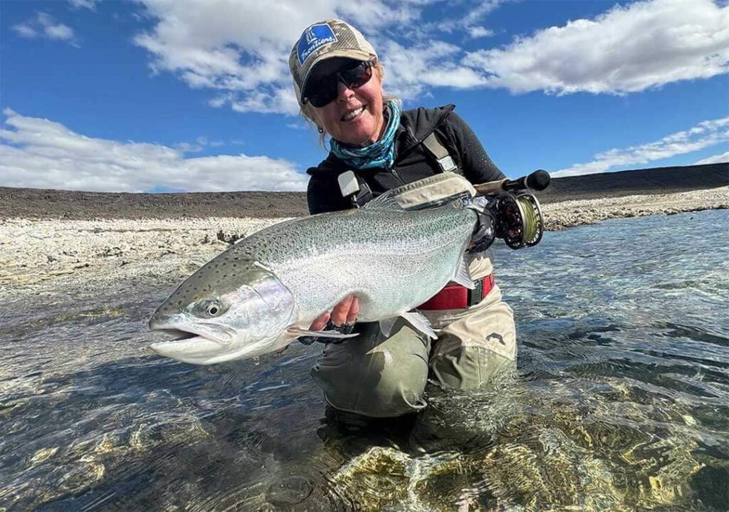 A woman holding up a large fish in the water.