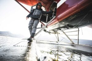 Person stepping out of a seaplane onto a wet surface.