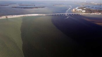 Aerial view of a bridge spanning over a body of water with visible water discoloration.