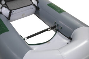 Close-up of the interior of an inflatable boat showing a gray and green color scheme, seating area, and attachment points along the sides.