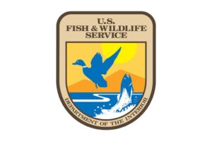 U.S. Fish & Wildlife Service logo featuring a blue duck in flight and a fish jumping from water, set against a yellow sun and orange hills background.