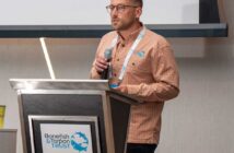 A man wearing glasses and a Bonefish & Tarpon Trust shirt speaks into a microphone at a podium with the organization’s logo during a presentation.